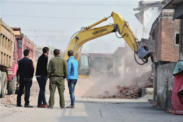 几名村民在观望大型机械进行拆除作业。
